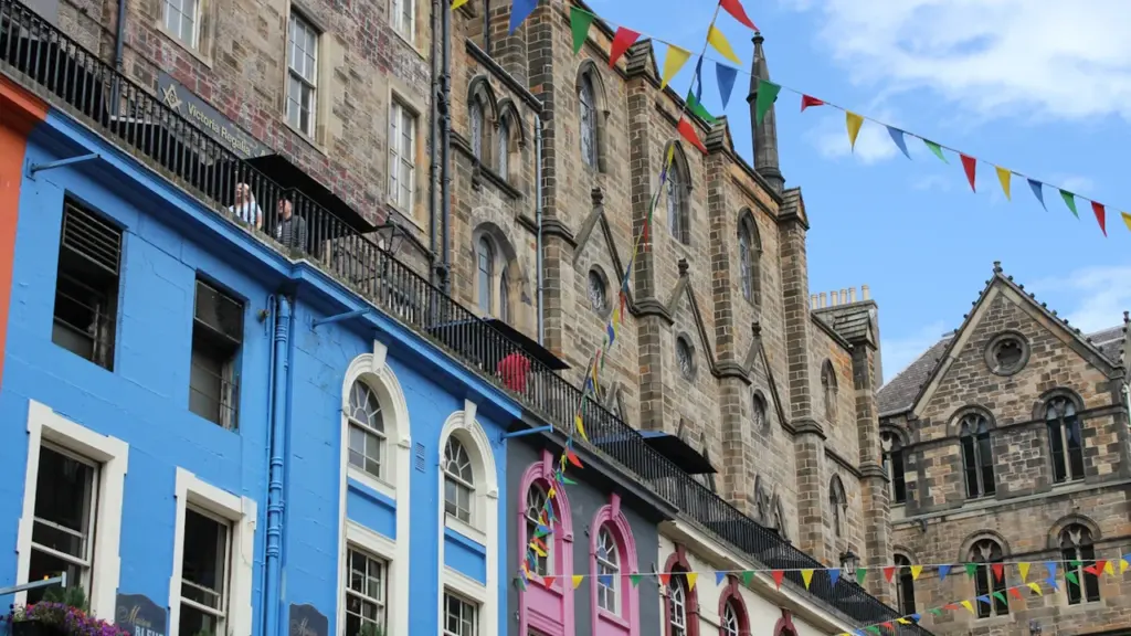 Colorful historic buildings decorated with vibrant bunting on a sunny day in Edinburgh.