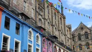 Colorful historic buildings decorated with vibrant bunting on a sunny day in Edinburgh.