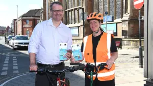 A man and a woman in high-visibility gear holding Hull Cycle Map brochures outdoors.