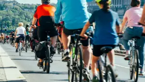 Group of cyclists riding bicycles on a paved road during a community event.