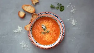 A rustic bowl of tomato soup garnished with fresh basil leaves