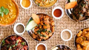 Top-down view of various Indian curry dishes served on a woven table mat.