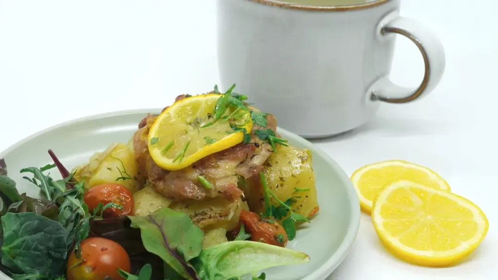 A fresh warm potato and fish salad served with lemon on a plate.