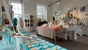 A bright boutique store filled with handmade gifts, jewelry, and framed artwork on display.