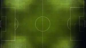 High angle aerial view of a professional green soccer pitch at night.