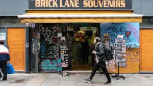 A pedestrian walking past a souvenir shop on a London high street.