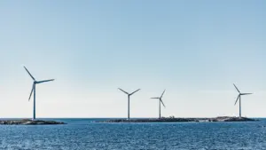 An expansive offshore wind farm set in deep blue sea under clear skies.