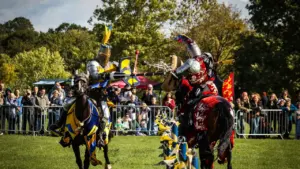 Two armored knights on horseback collide while jousting during a medieval festival tournament.