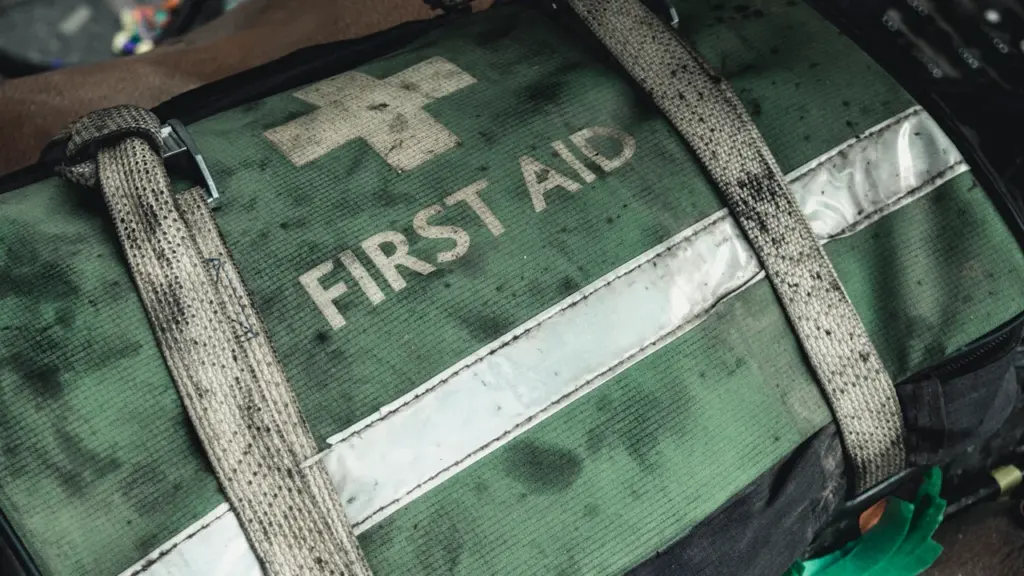 A weathered green and black first aid bag with reflective safety stripes.
