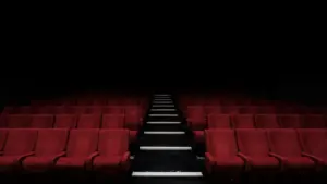 Empty rows of red velvet cinema seats in a dark movie theater auditorium.