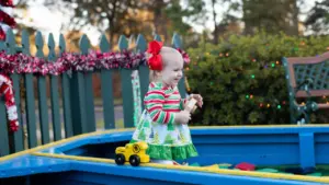A young child plays in a blue outdoor play structure at a public park.