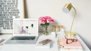 A clean, organized desk setup featuring a laptop, study lamp, and notebooks.