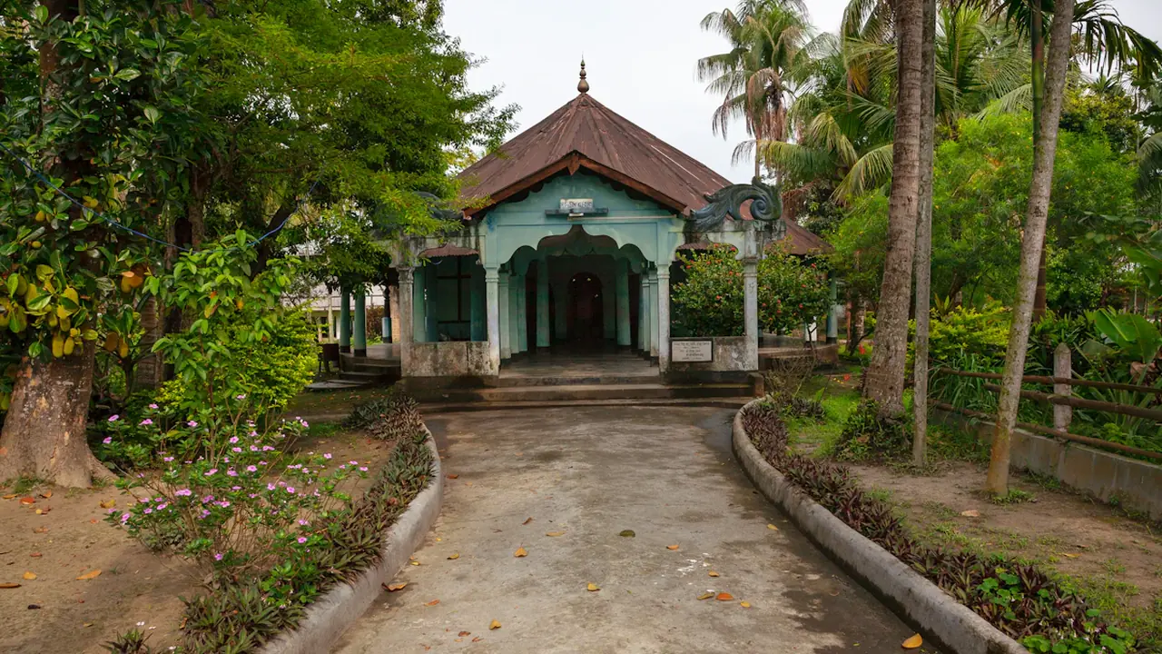 A traditional stone building with a pathway surrounded by lush green trees