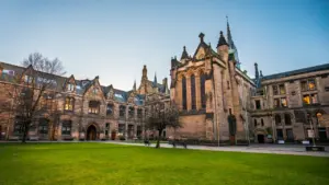 Classic gothic-style university building with a manicured green lawn at dusk.