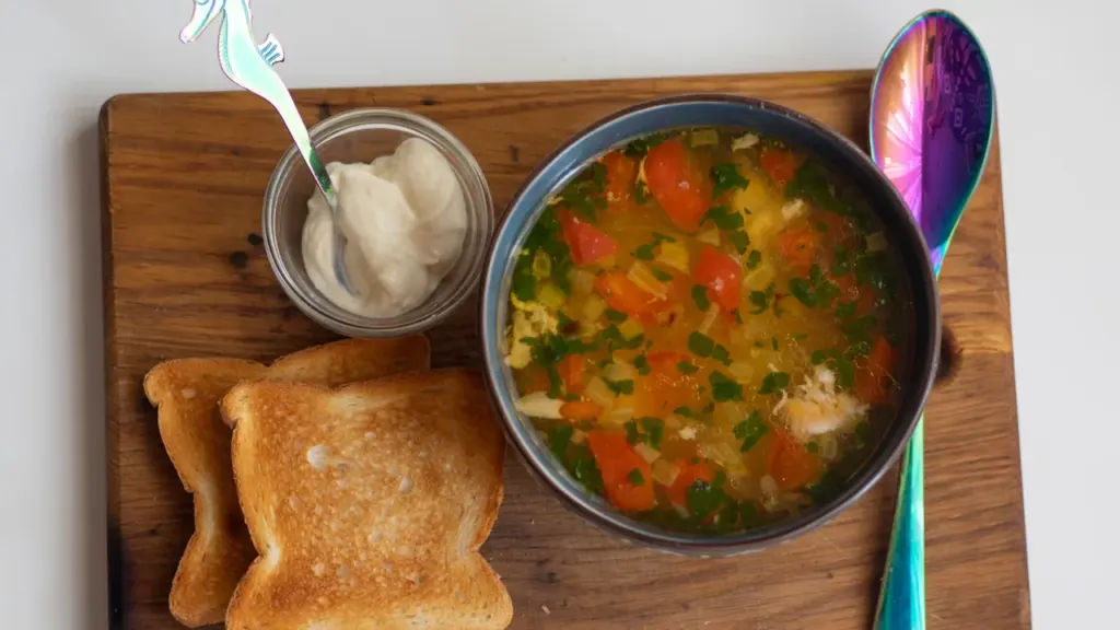 Bowl of vegetable soup with toast served on a wooden board