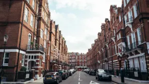 Classic London residential street featuring tall, traditional red brick terraced houses.