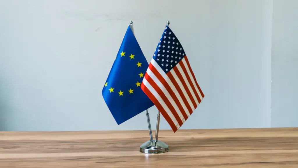 European Union and United States flags displayed together on a wooden office table