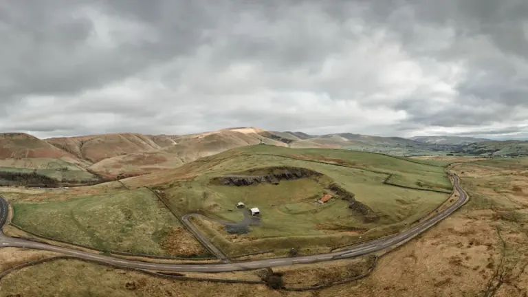 Panoramic view of rolling hills and a winding road under a cloudy sky