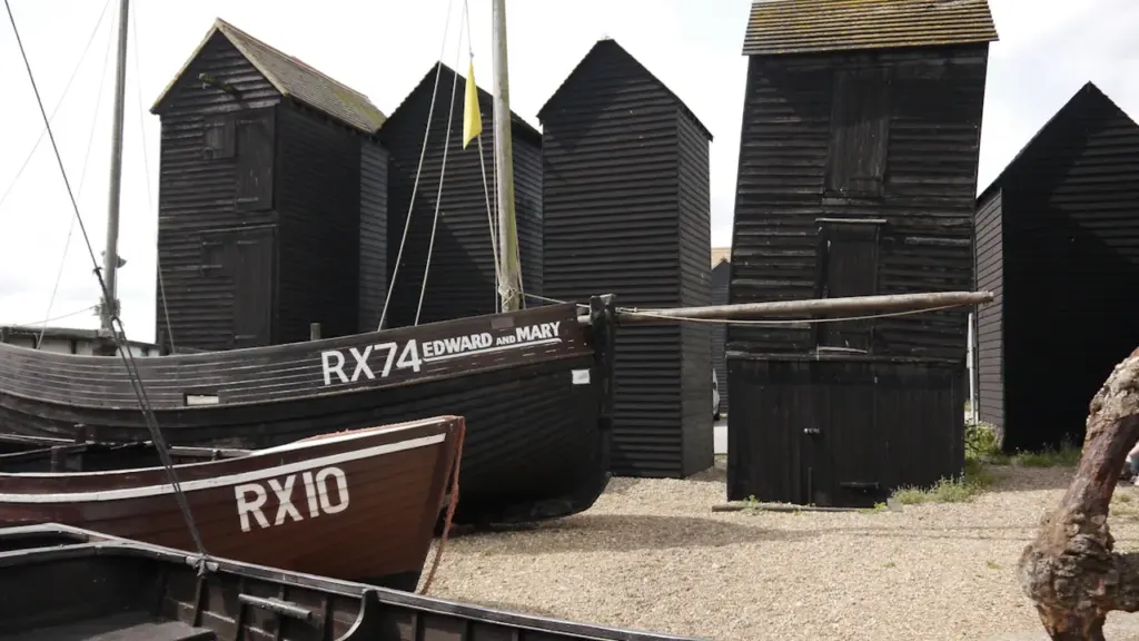 Traditional wooden black net shops and fishing boats on the beach in Hastings, UK.