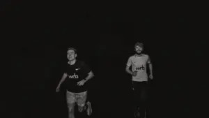 Two men running at night, captured in a moody and atmospheric black and white photo.