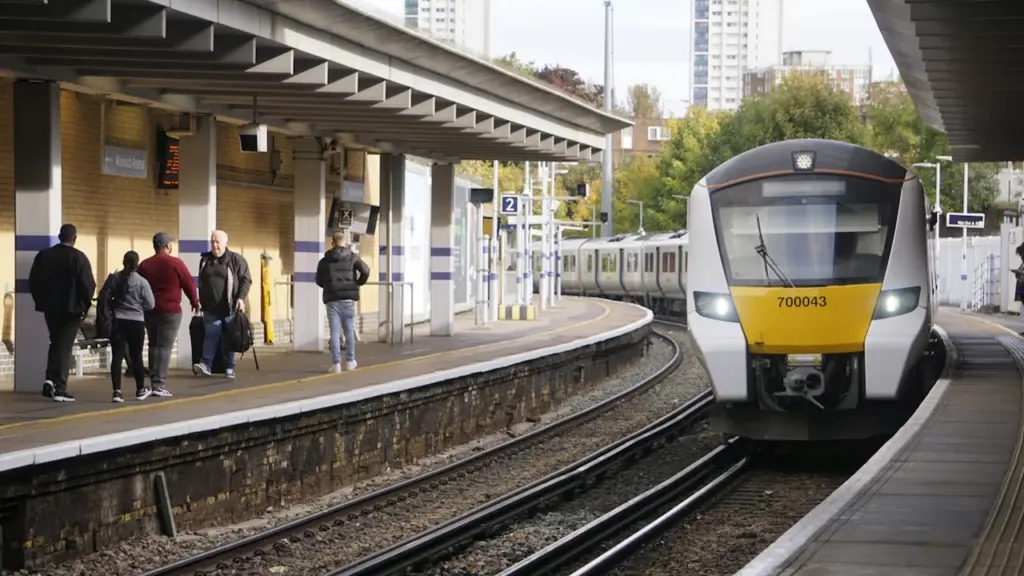 A modern commuter train arriving at a UK railway station platform.
