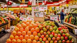 Produce section in a supermarket with various fruits and price tags clearly displayed.