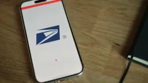 Smartphone displaying a delivery company logo on a wooden office desk surface.