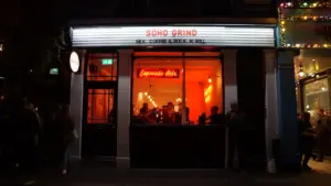 The illuminated storefront of a Soho coffee house at night in London.