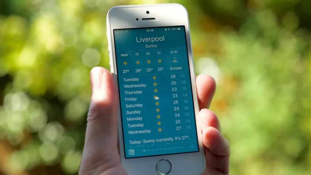 Close up of a hand holding a smartphone showing a local UK weather forecast