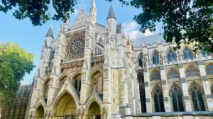 The historic West Front of Westminster Abbey under a bright blue London sky.
